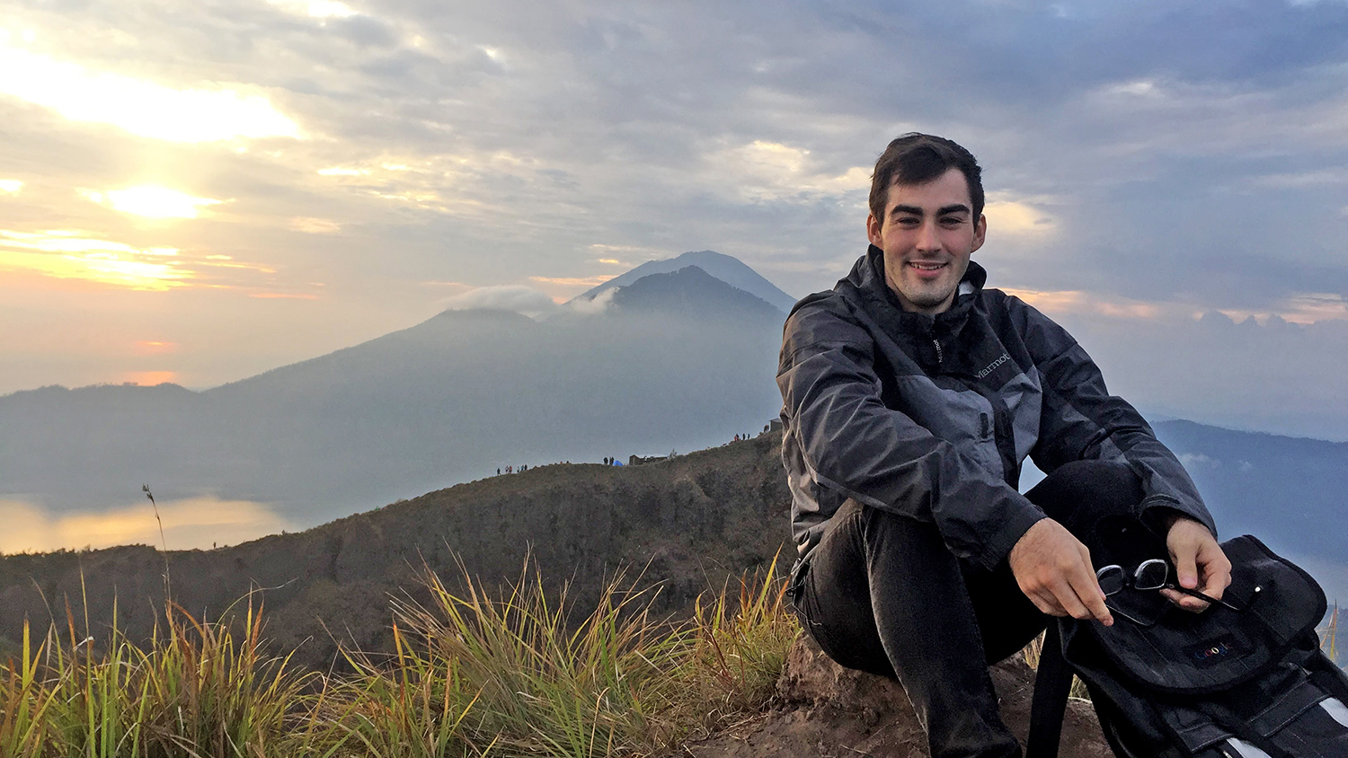 A student sits on a mountaintop during a study abroad trip
